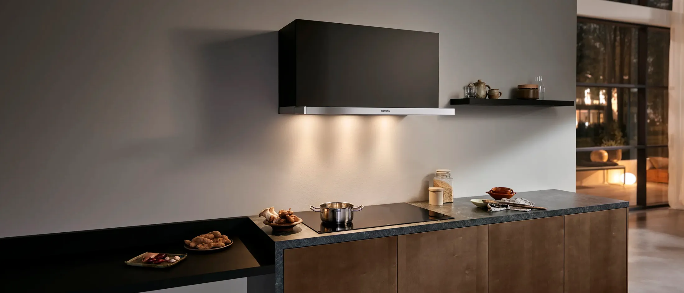Uma cozinha moderna com armários pretos elegantes, uma chaminé minimalista e uma bancada com pratos, criando um espaço culinário estiloso.
