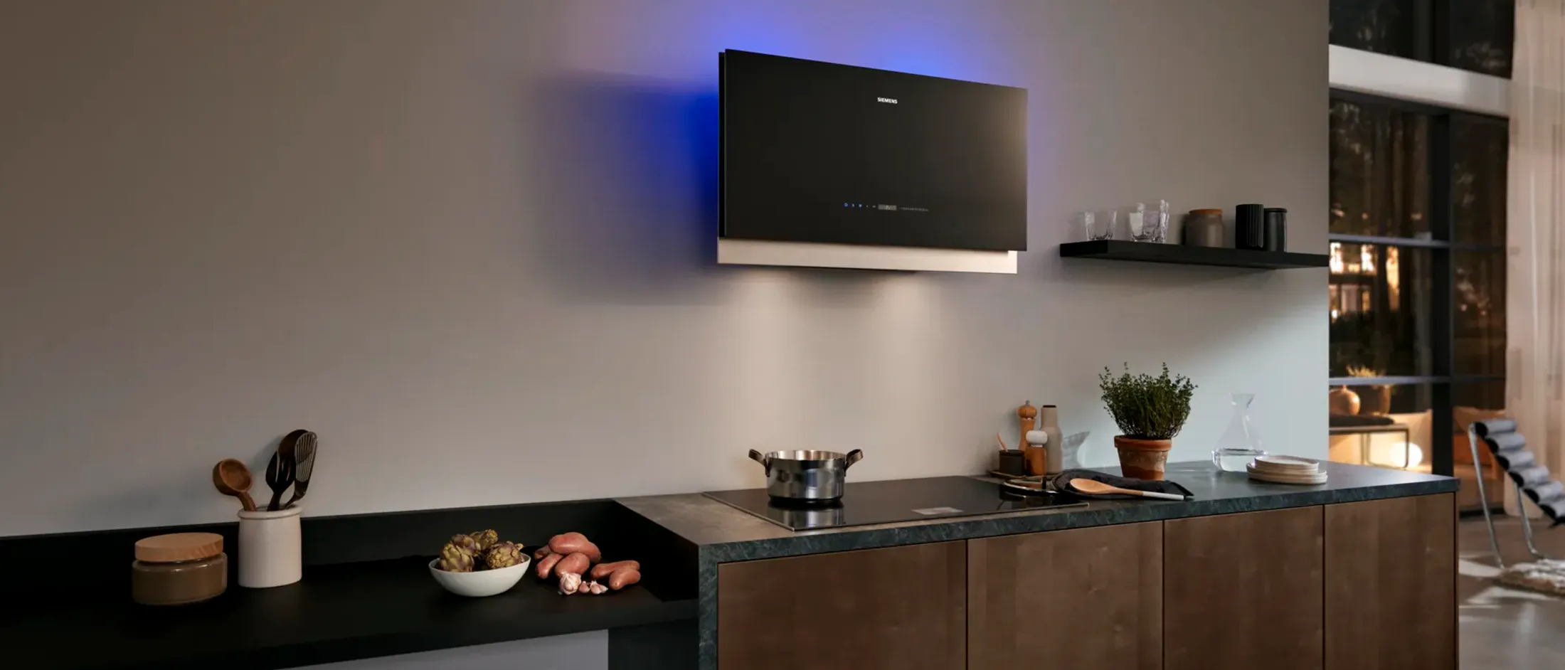 Modern kitchen featuring a sleek, black hood with blue lighting, paired with an induction cooktop and stylish decor.