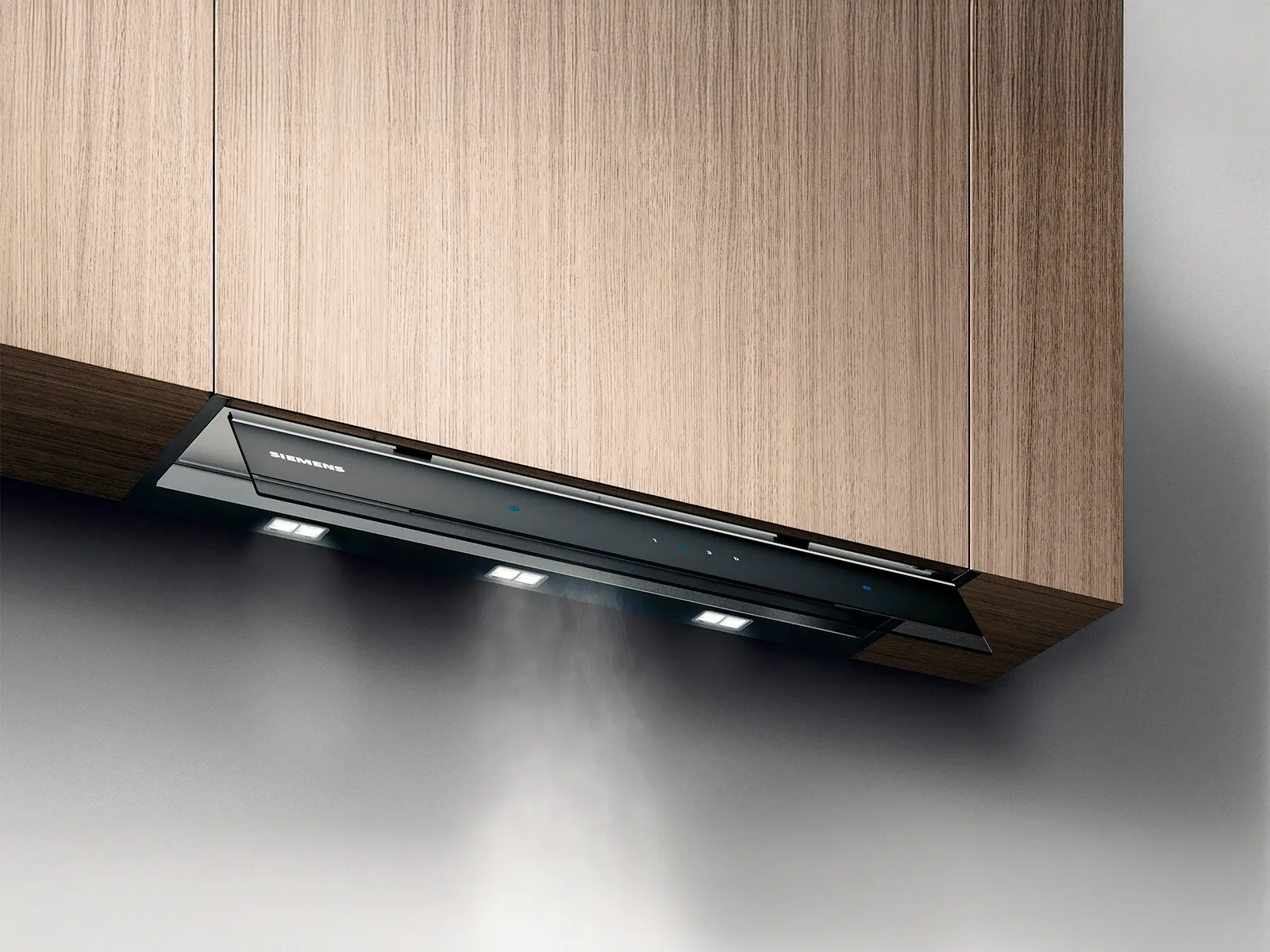 Une hotte de cuisine Siemens élégante installée sous des meubles en bois, dégageant de la vapeur, avec des lumières intégrées illuminant la zone de cuisson.