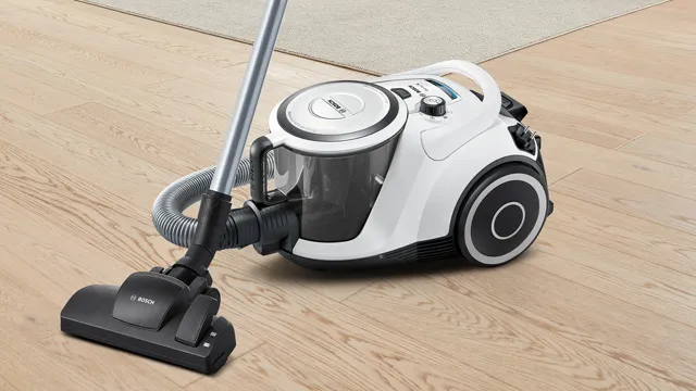 Ein weißer Bosch-Staubsauger mit transparentem Staubbehälter steht einsatzbereit auf einem Holzboden.