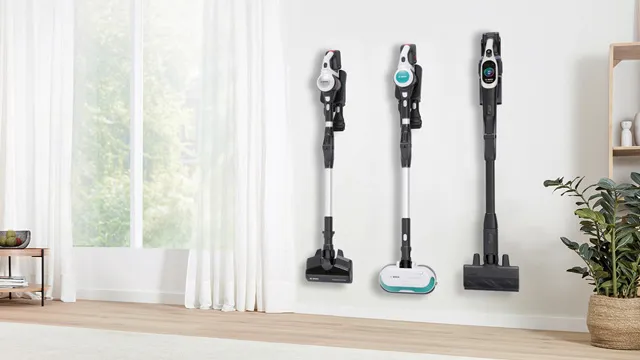 Drei kabellose Staubsauger sind an einer Wand in einem hellen Raum mit großen Fenstern und leichten Vorhängen montiert und zeigen ein modernes, ordentliches Ambiente.