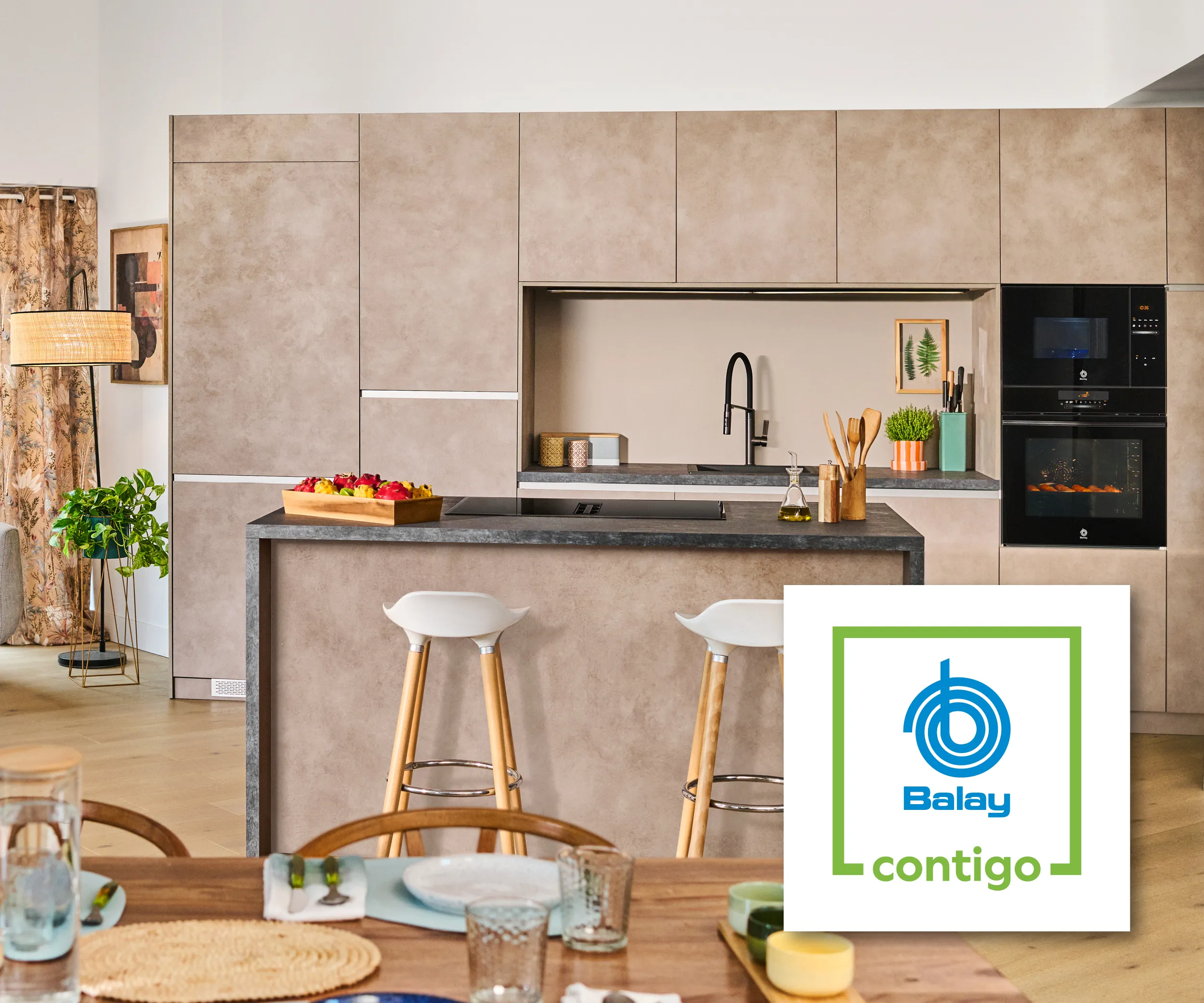 Cocina moderna y minimalista con armarios de color gris claro, electrodomésticos blancos, detalles en azul, plantas verdes grandes y luz natural proveniente de una ventana.