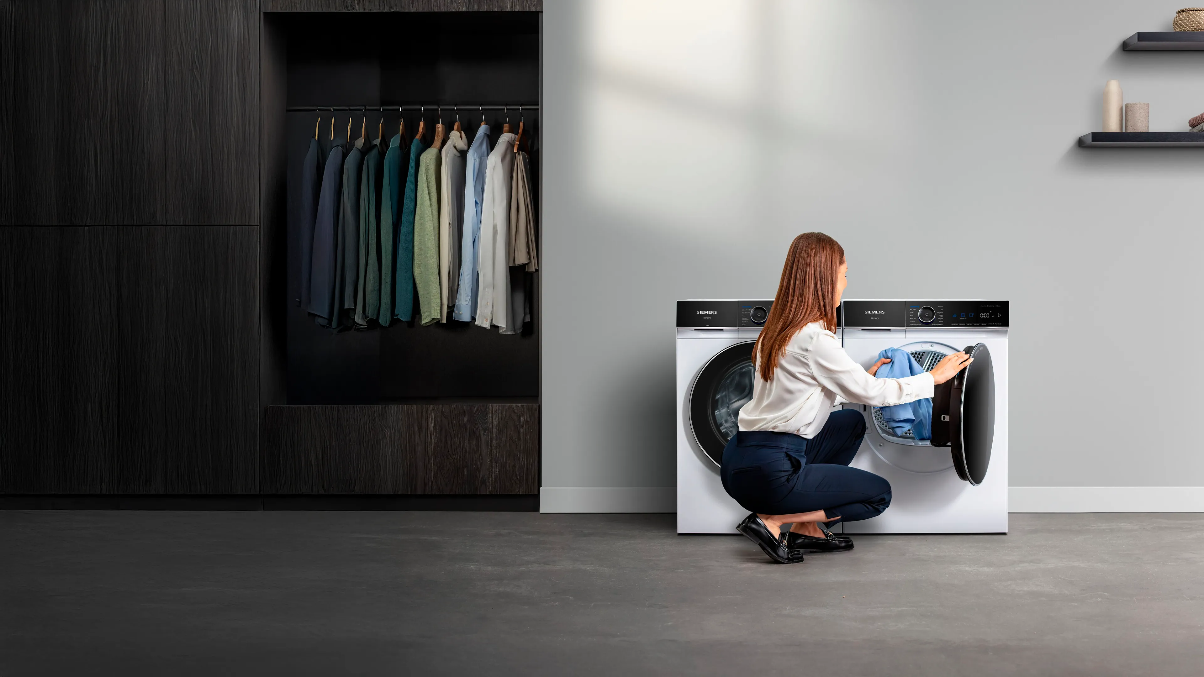 Eine Frau kniet vor einem iQ700 Trockner und legt Wäsche in die Trommel.