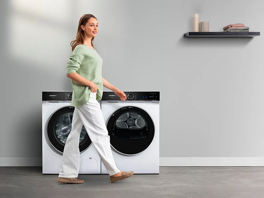 woman walking past a washing machine and tumble dryer