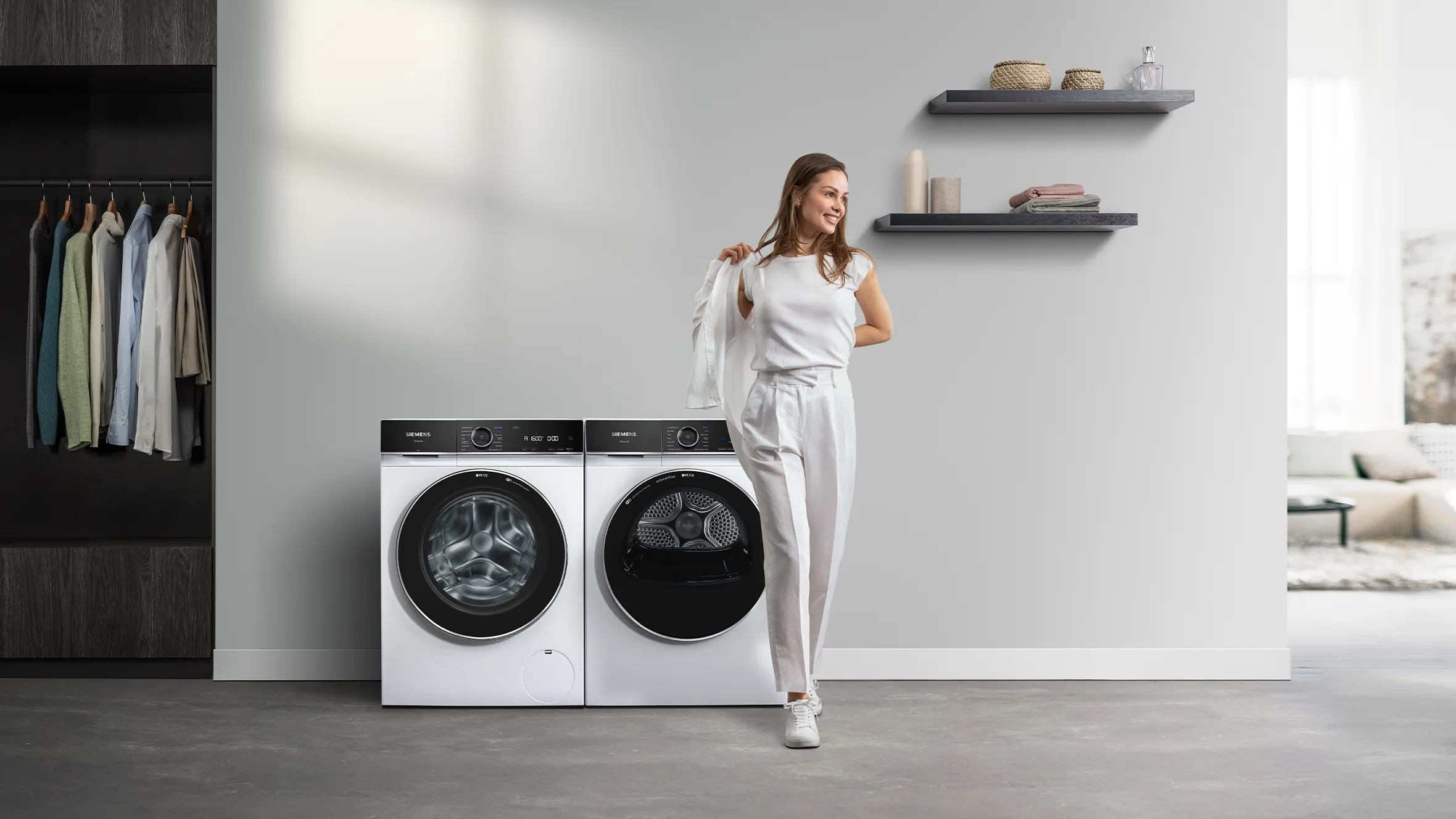 Smart woman standing next to washing machine and dryer