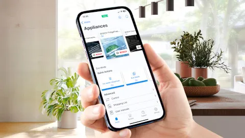 Bosch perilica rublja u modernoj kupaonici, u prvom planu s pametnim telefonom otvorenim na aplikaciji Home Connect