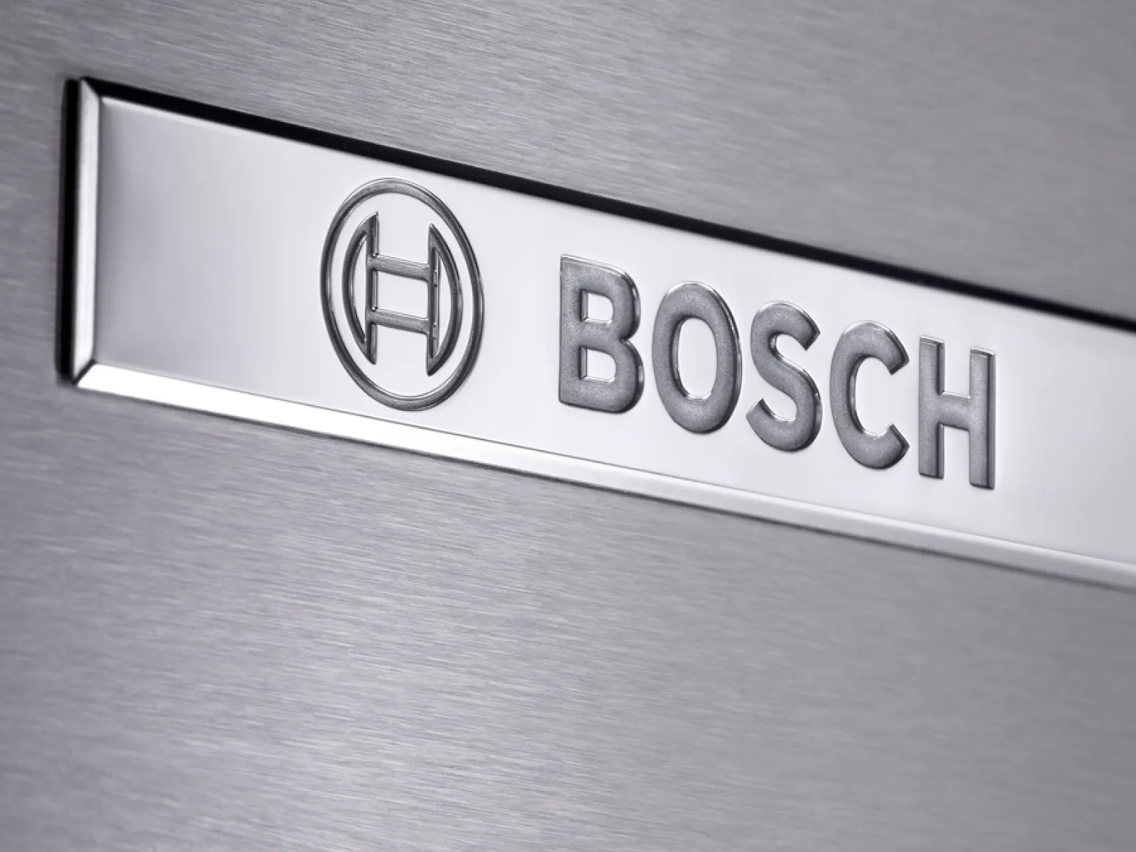 Nahaufnahme einer gebürsteten Edelstahloberfläche mit poliertem Bosch-Logo und -Emblem.