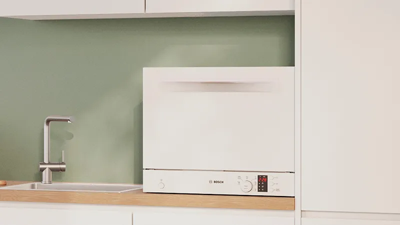 A modern kitchen corner featuring a Bosch dishwasher, minimalist sink, and a cookbook.