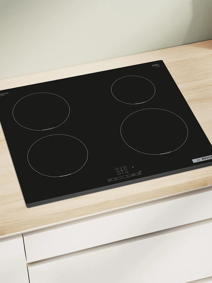 Three sleek, modern black hobs are shown. The left one has red heating zones, the middle features a vent, and the right has induction zones.