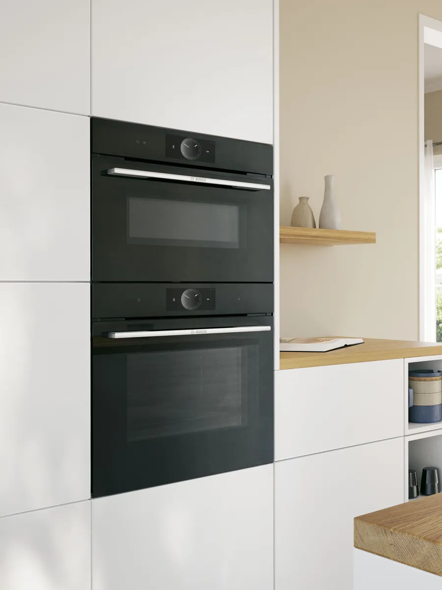 Bosch ovens built into white cabinets in light style kitchen.