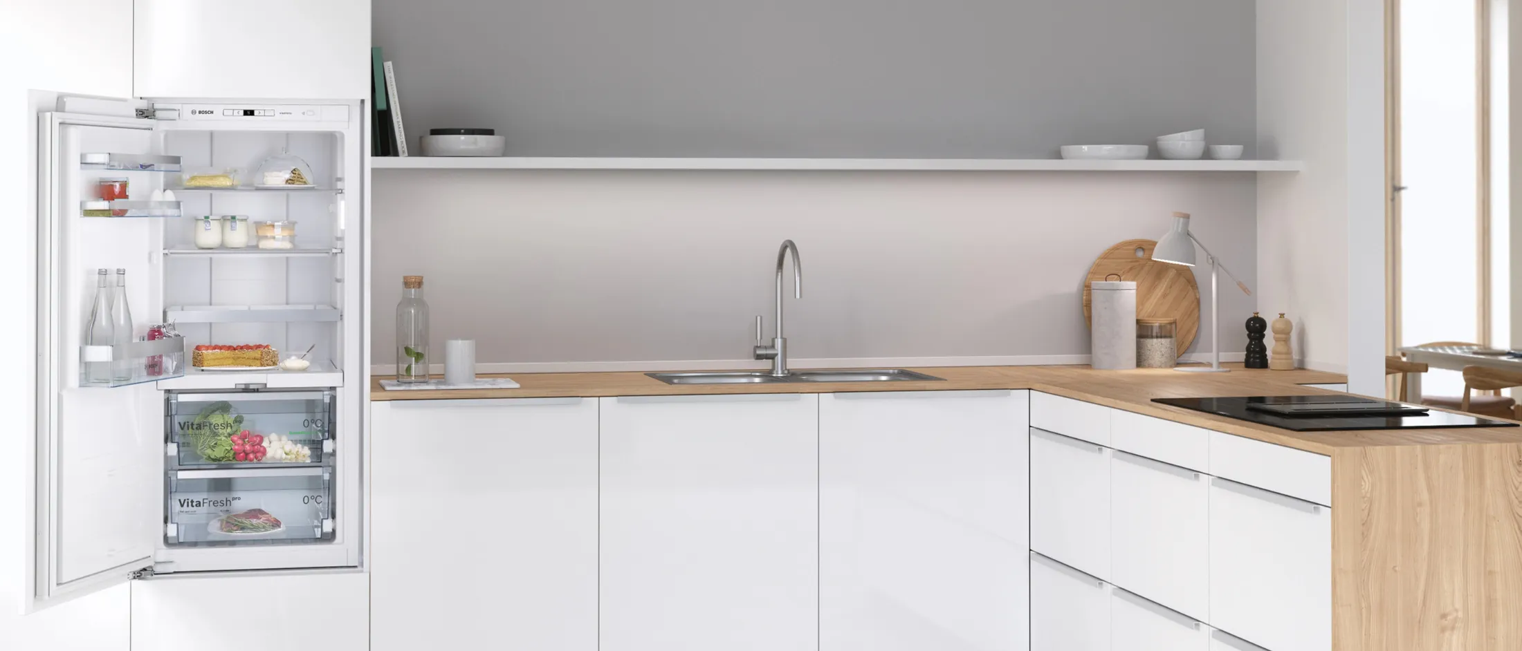 Modern kitchen with a white fridge and cabinets, wood counter, open fridge door, and a window.