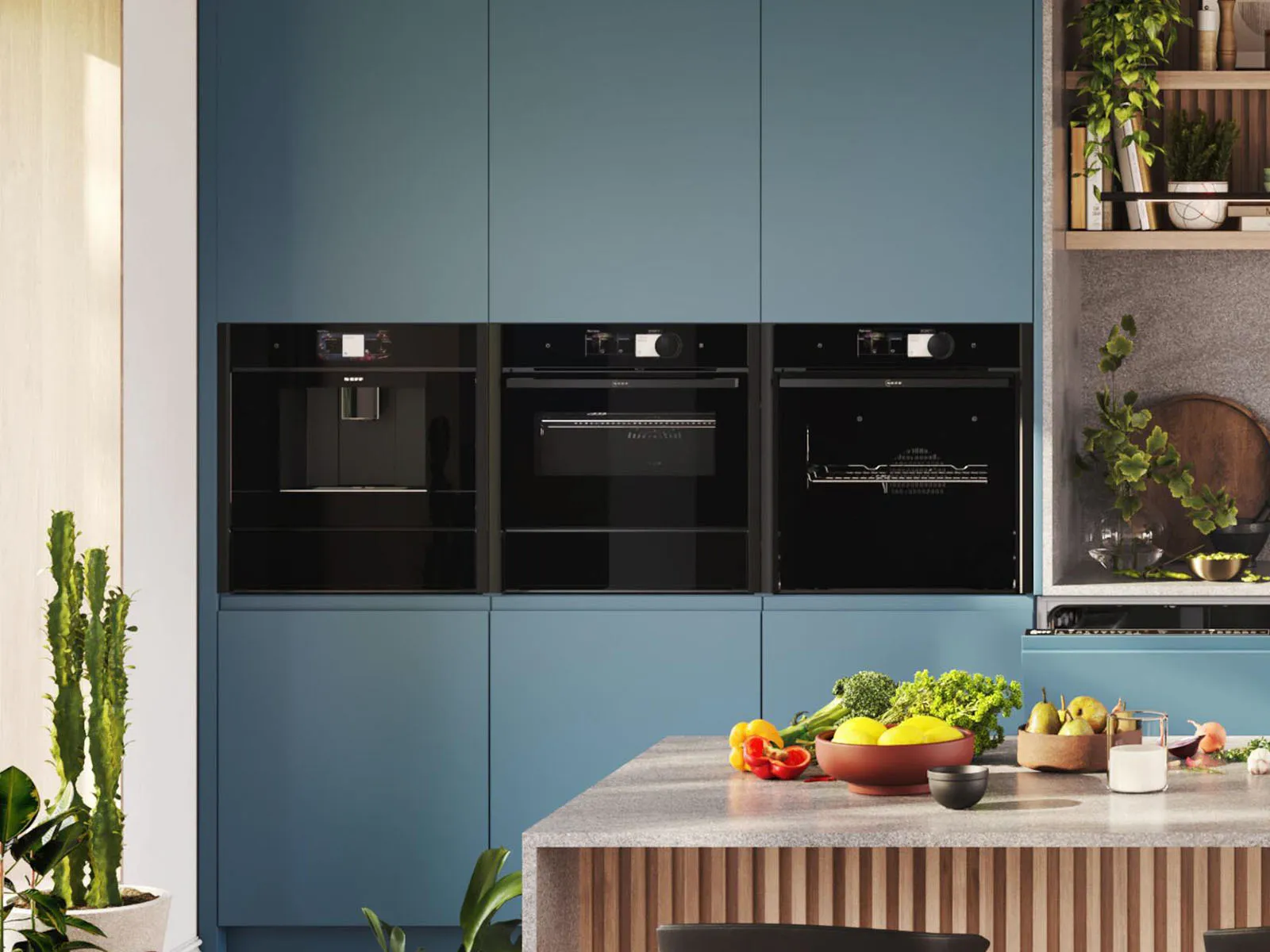 Moderne keuken met blauwe kastjes, drie zwarte apparaten en een grijs aanrechtblad waarop verse groenten en fruit staan ​​uitgestald.