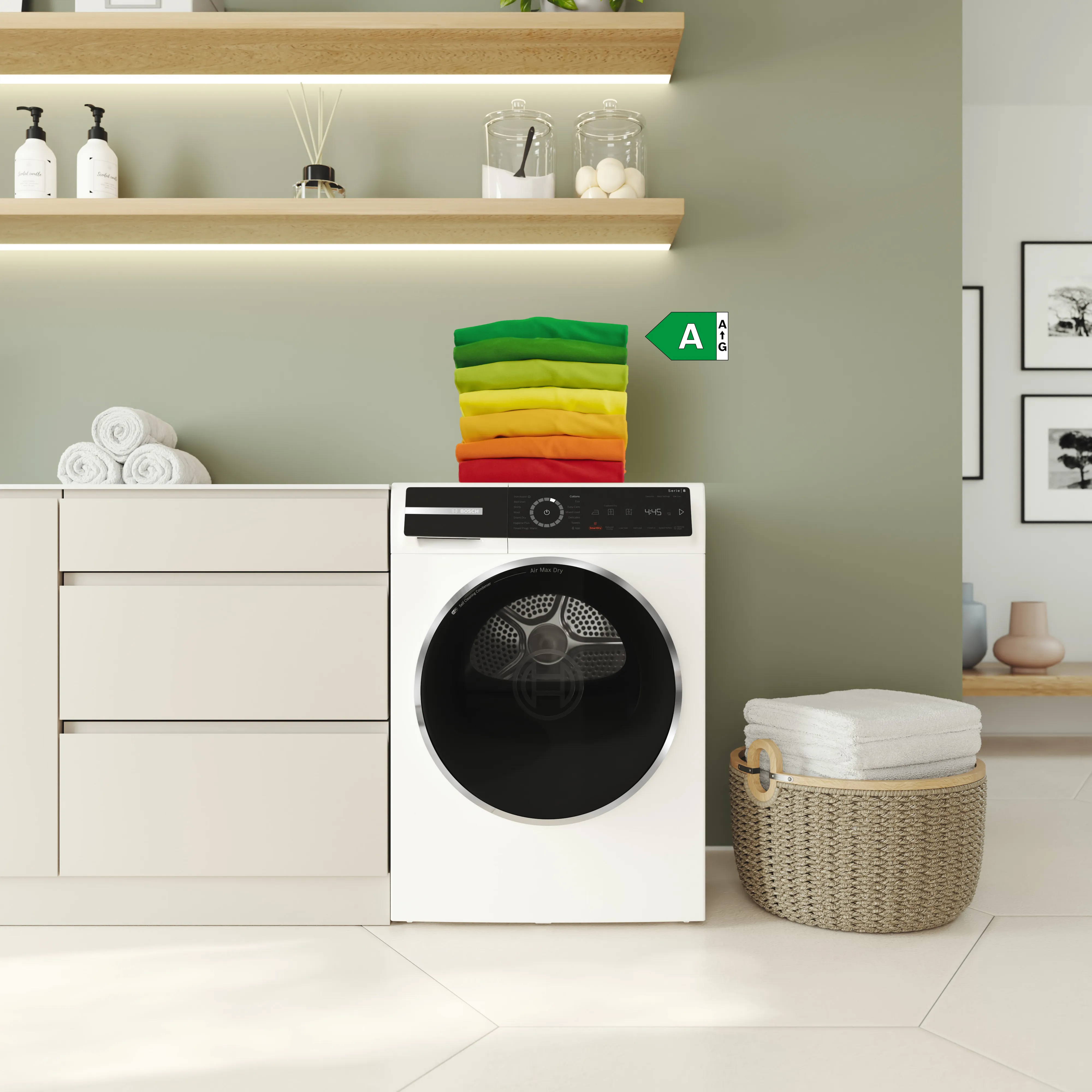 Pe un uscător de rufe Seria 8 de la Bosch sunt stivuite mai multe prosoape în culorile etichetei energetice. O săgeată suprapusă cu clasa energetică A indică spre prosopul verde.