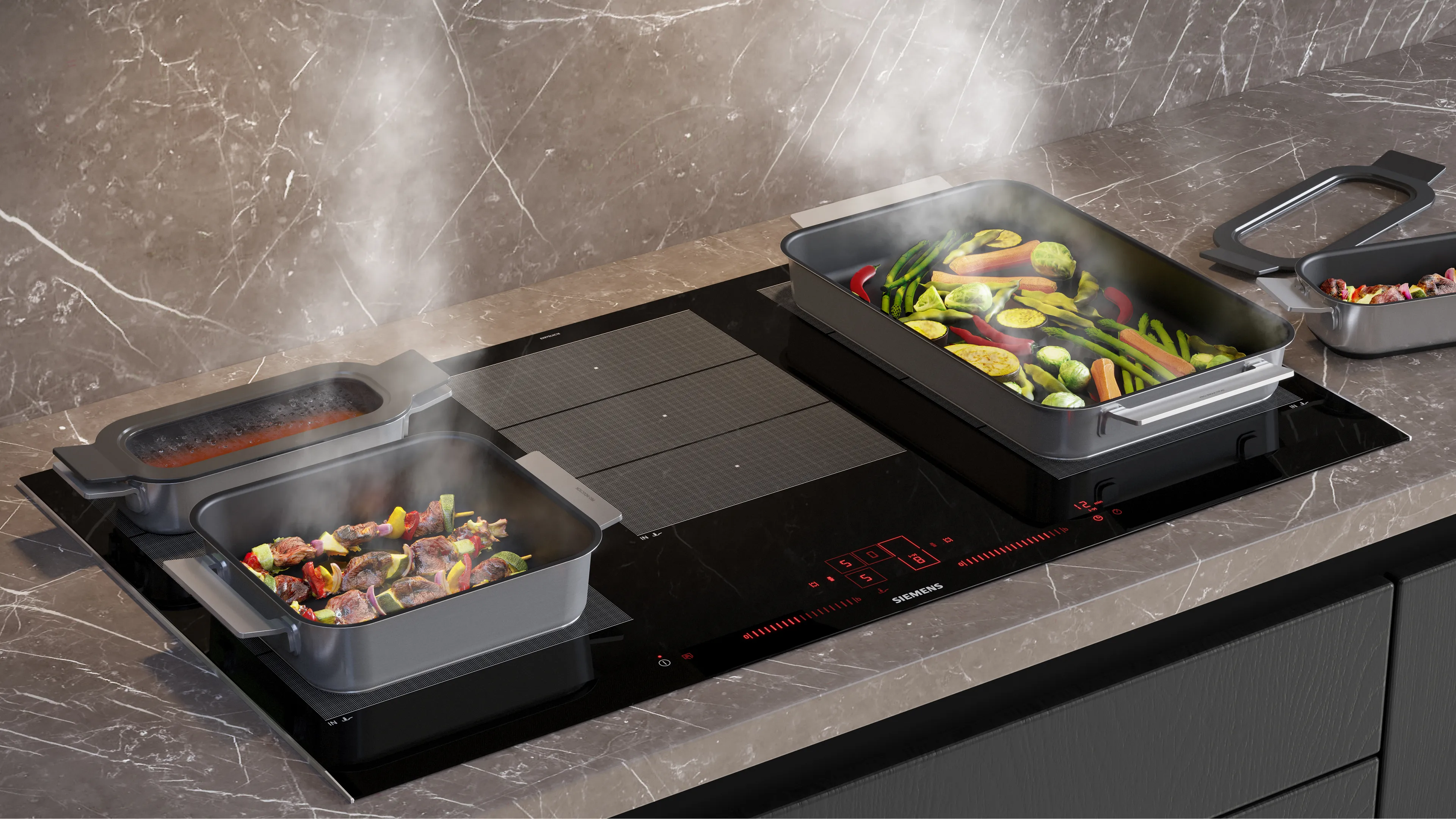 Piano cottura a induzione con due pentole quadrate che cuociono verdure e carne con vapore visibile.