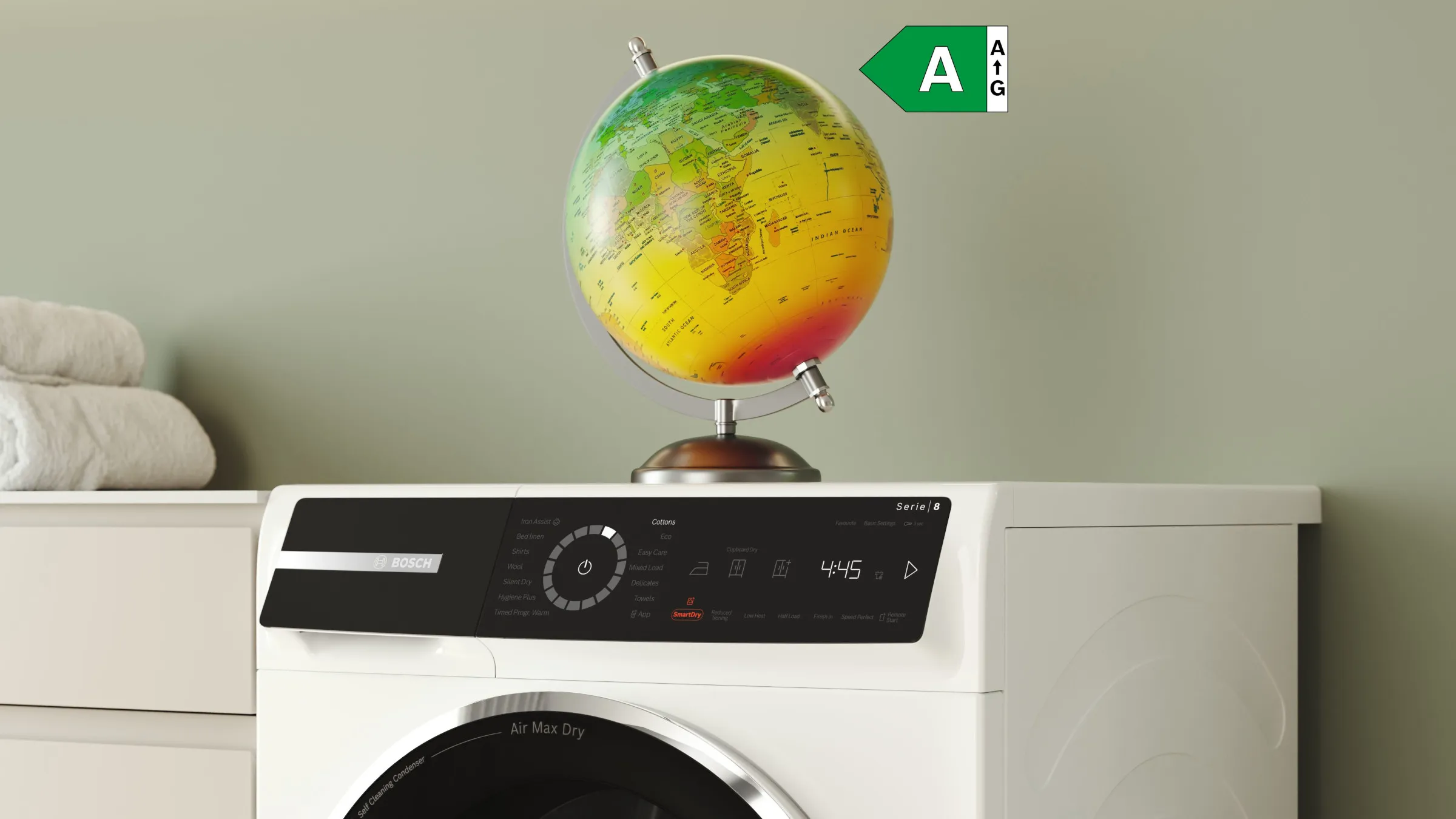 En modern tvättmaskin med en snygg kontrollpanel och en färgglad jordglob ovanpå, placerad mot en ljusgrön bakgrund.