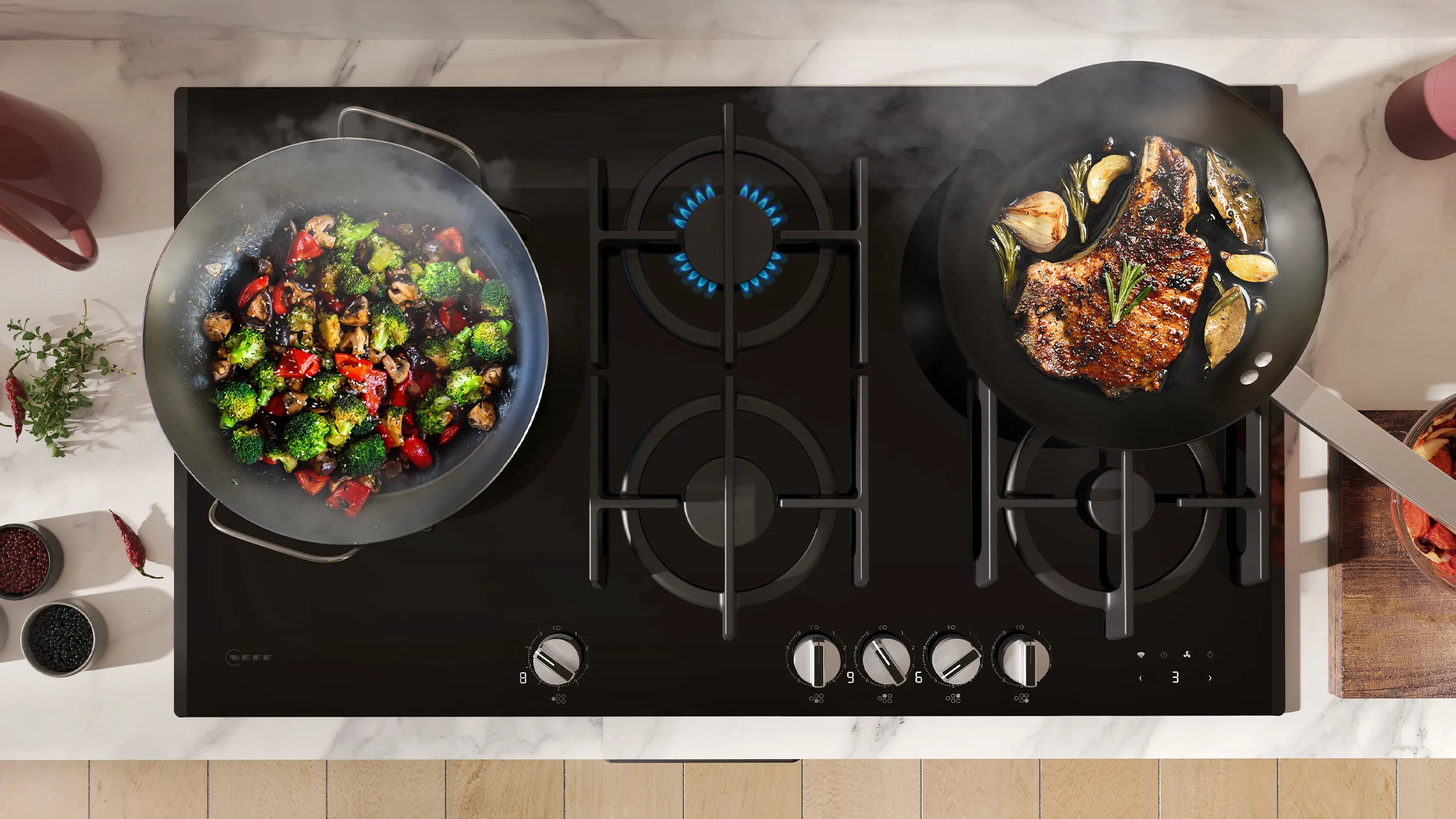 A gourmet kitchen scene featuring a black gas stovetop with stir-fried vegetables and grilled meat in two skillets, emitting steam.