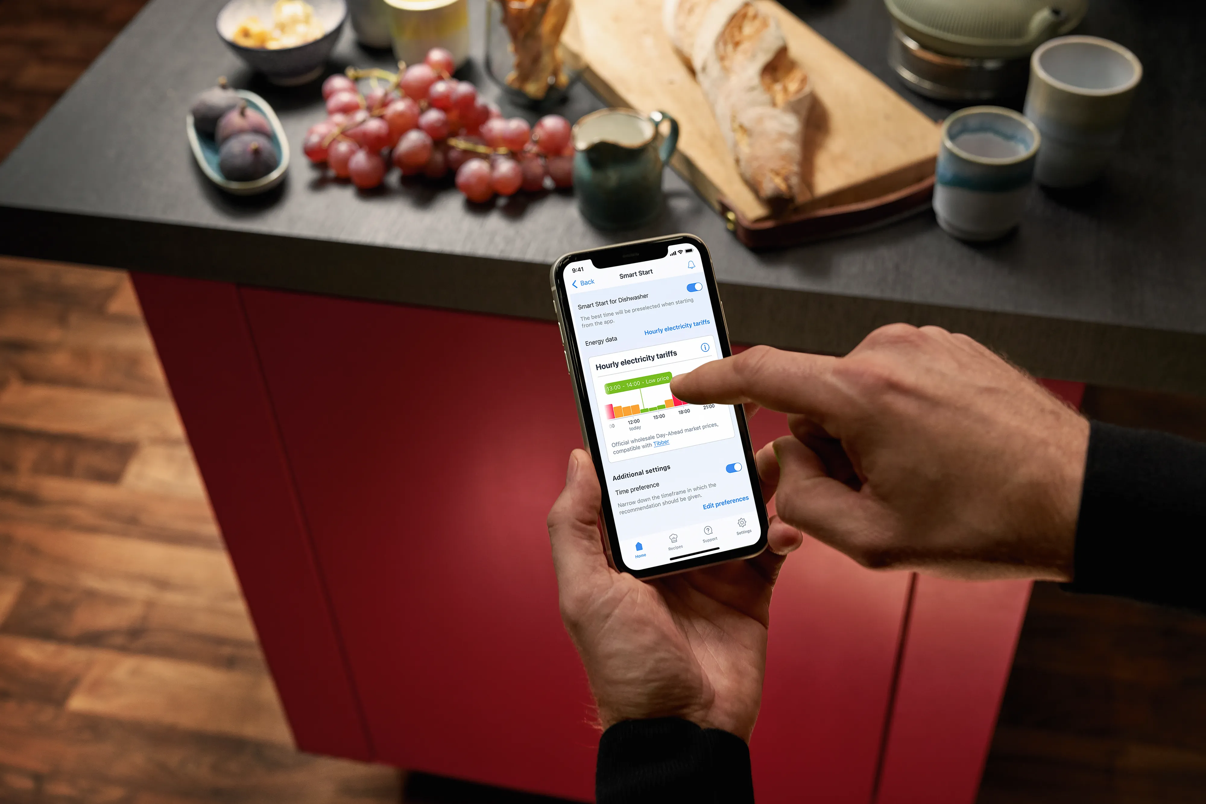 En person bruger en app – en køkkenbordplade med druer i baggrunden