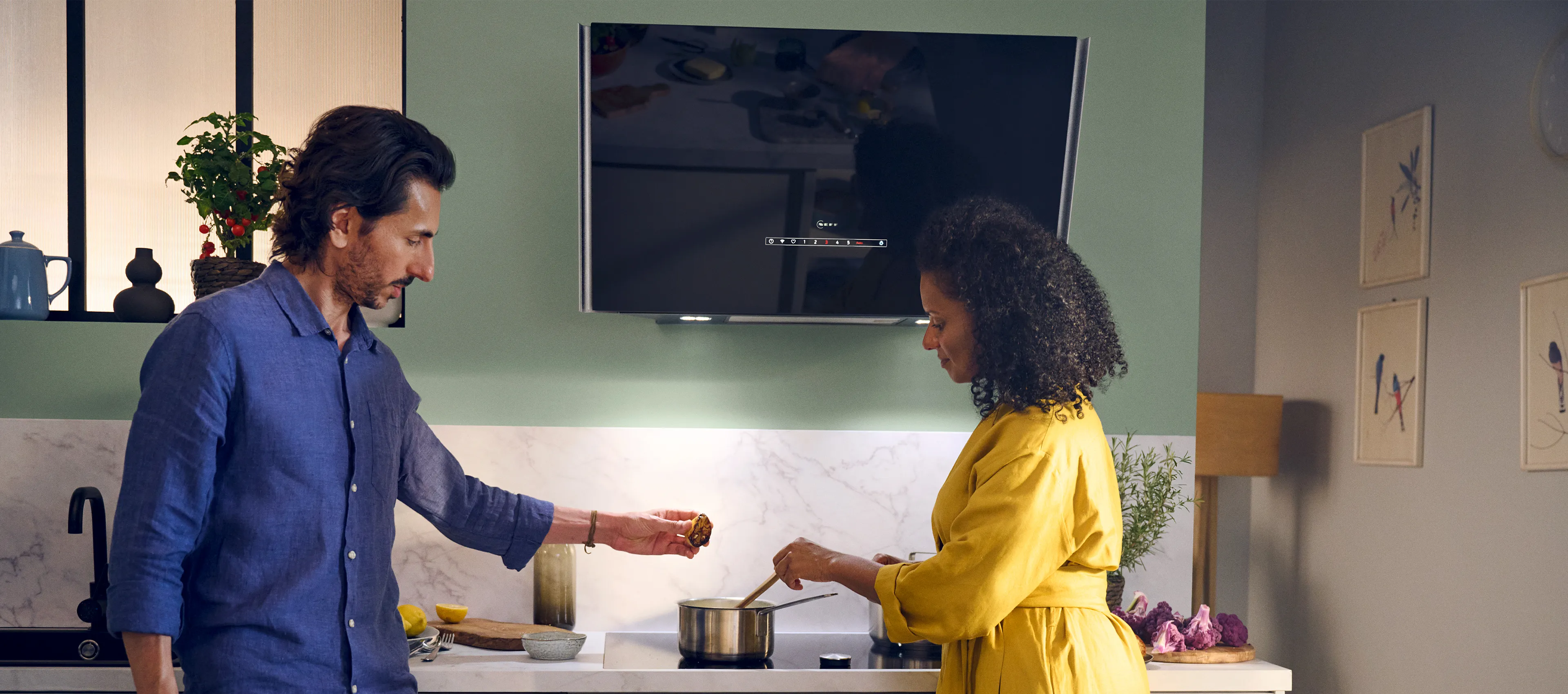 A man and woman cooking together in a kitchen, using an induction hob to prepare their meal. 