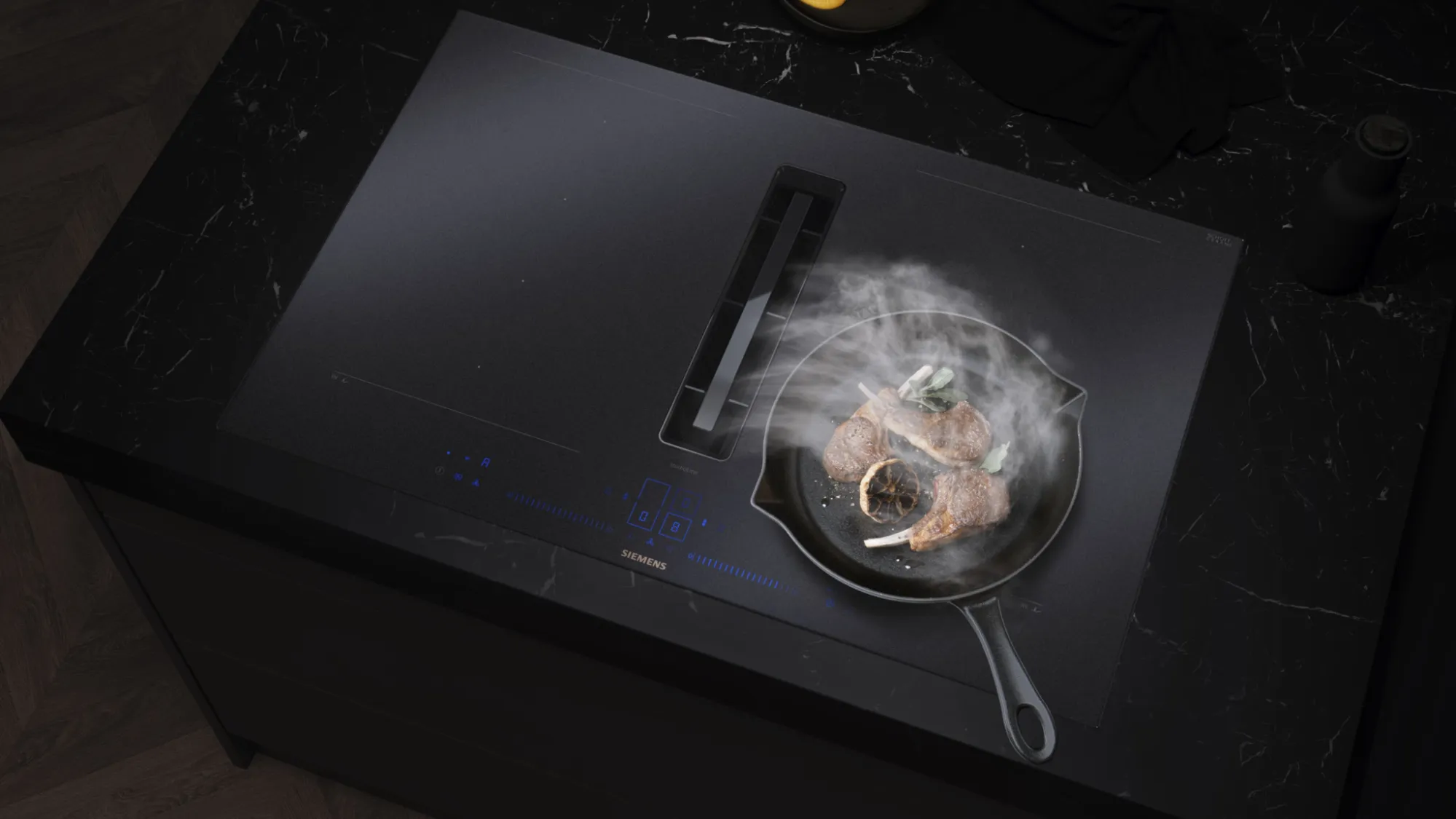 Cuisson à la vapeur de côtelettes d'agneau dans une poêle sur une plaque à induction noire Siemens avec ventilation intégrée.