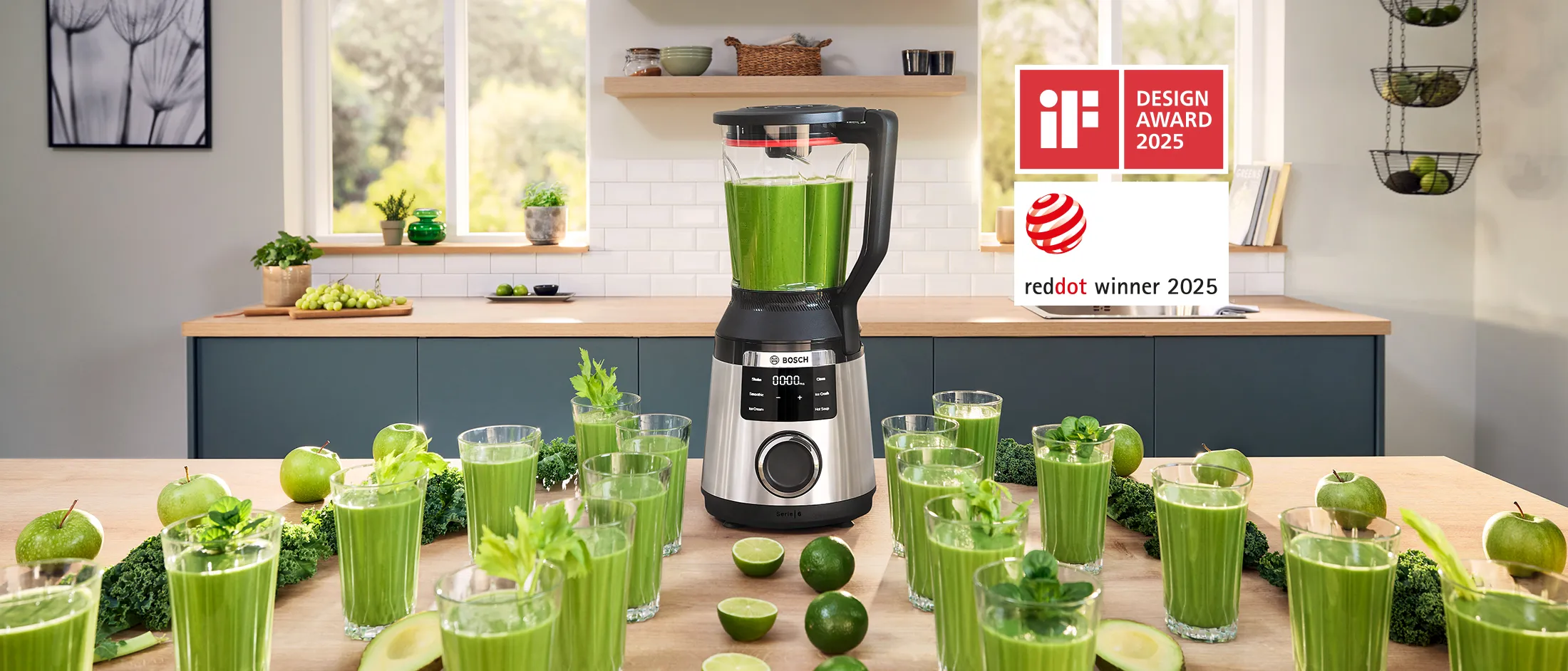VitaPower Serie 6 otoczony szeregiem szklanek z zielonym smoothie, awokado i limonkami na kuchennym stole.