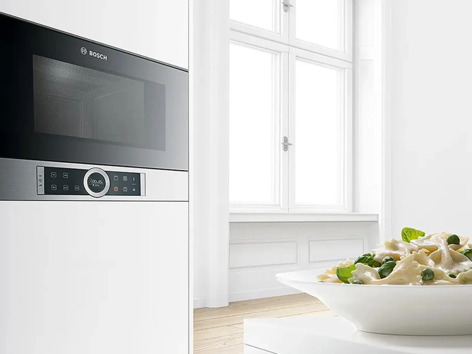 Built-in microwave with open door in modern kitchen, showing sleek interior design and controls.