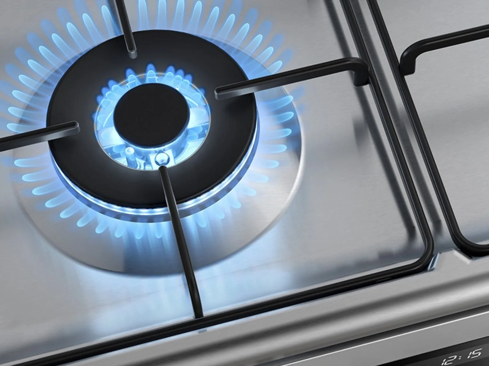 Nahaufnahme eines Gaskochfeldbrenners, blaue Flammen, die von einem runden Brenner auf einer glänzenden Edelstahloberfläche ausgehen.