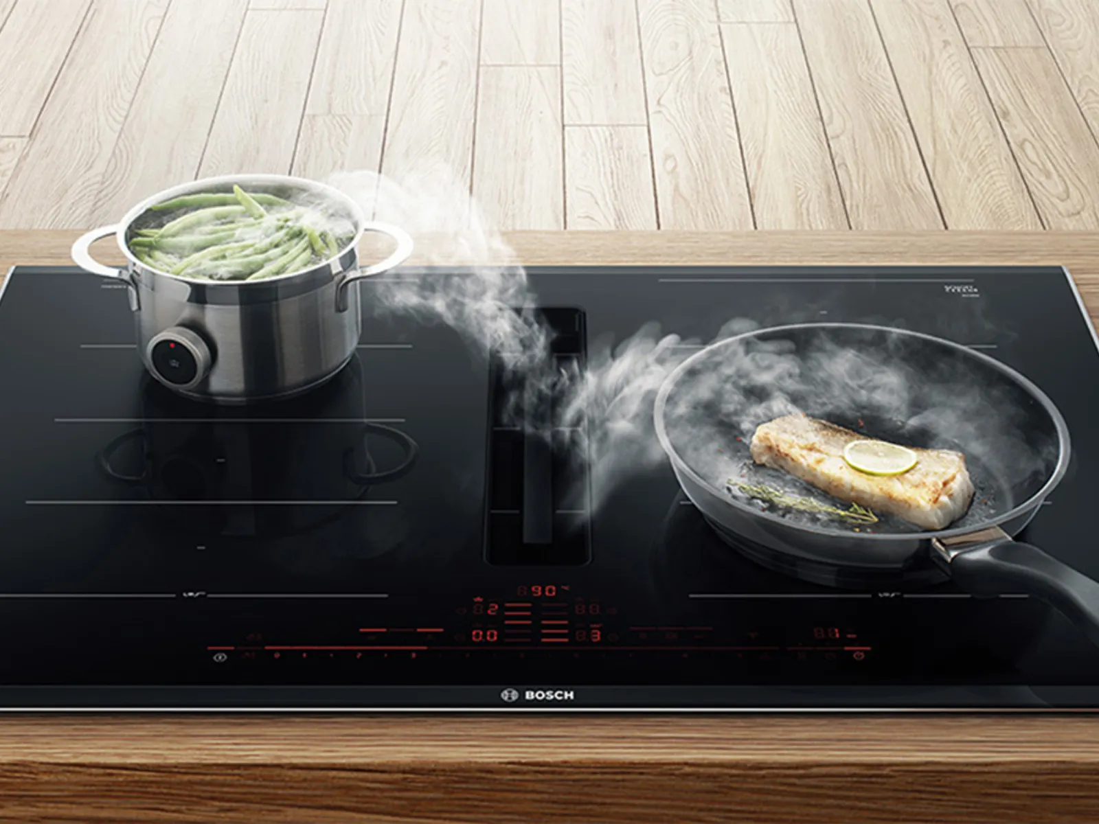 Kochen auf einem modernen Induktionskochfeld mit einem Topf dampfenden Gemüses und einer Pfanne mit brutzelndem Essen.
