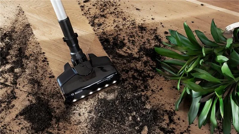 Vacuum cleaner with LED lights on cleaning up dirt from a spilt plant.