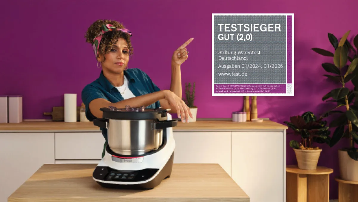 Eine Frau steht neben einem Cookit und präsentiert dessen Testerfolge.
