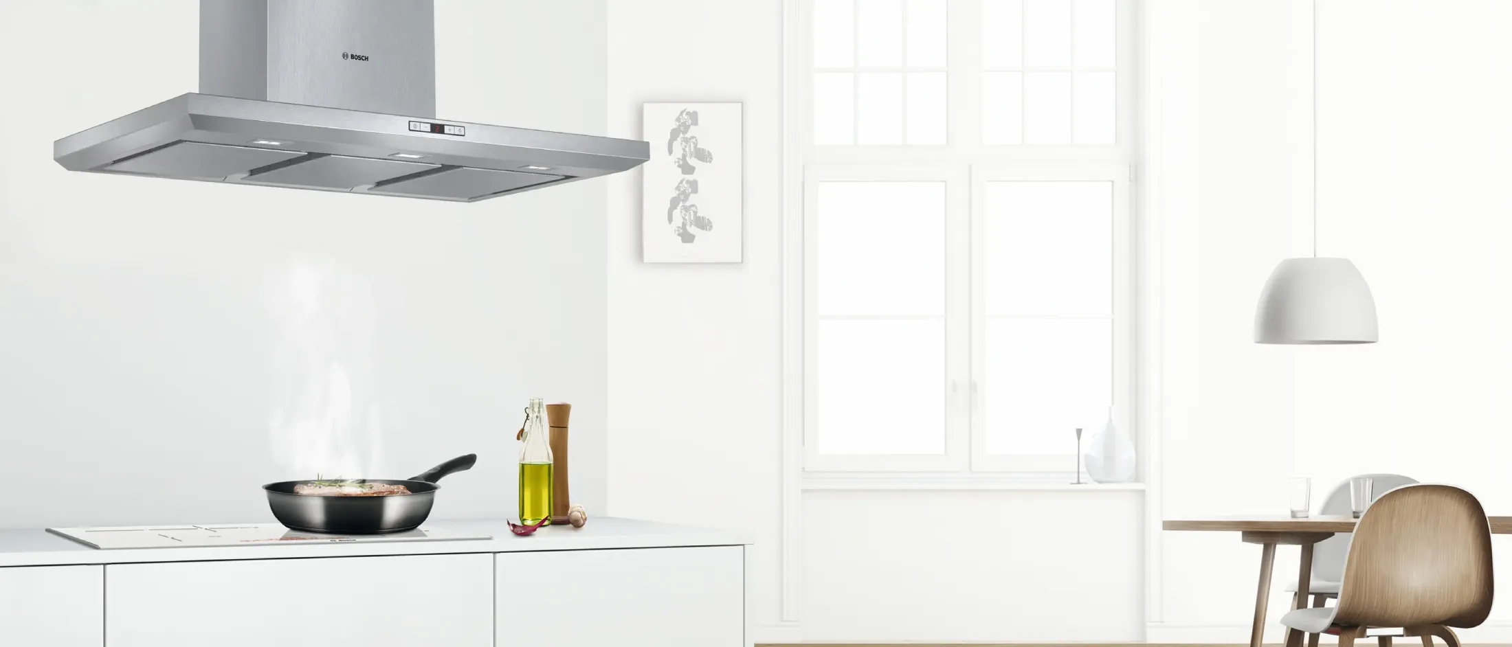 Modern kitchen with a sleek black hood, steam rising from a pan and wooden countertop.