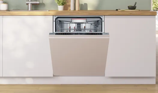 A Bosch integrated dishwasher, partially open, installed in a modern kitchen cabinet.