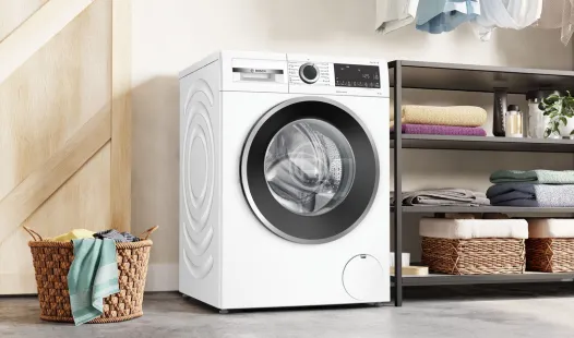A white Bosch front-load washing machine in a laundry room setting.