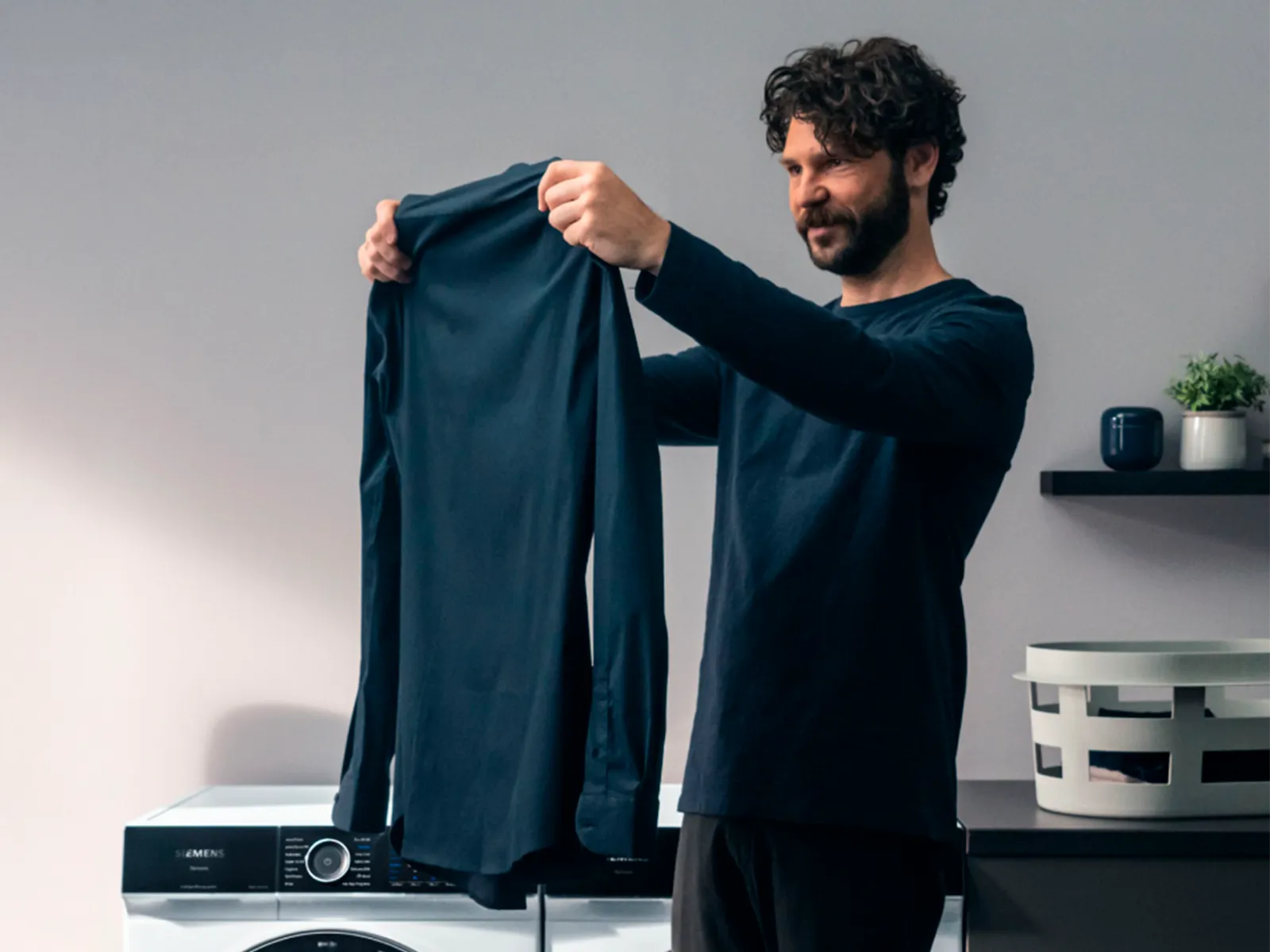 Ein Mann hält gewaschenes Hemd und betrachtet es.