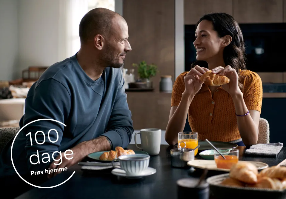 Par nyder morgenmad sammen med croissanter og juice, i et moderne hjemligt miljø.