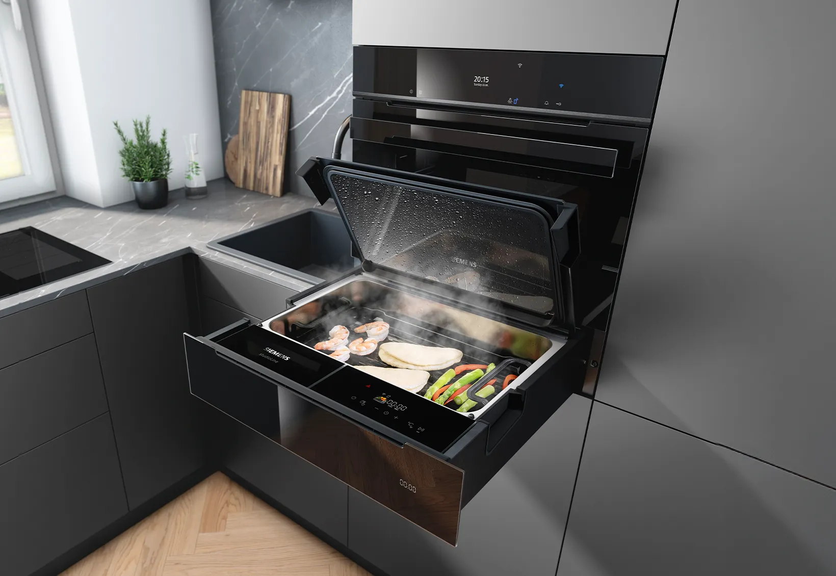 Tiroir-four vapeur Siemens noir encastré, tiré ouvert dans une cuisine moderne grise, révélant un plat fumant de crevettes, de filets de poulet et de légumes mélangés ; plan de travail en marbre, évier, planche à découper et pot de plantes aromatiques visibles.