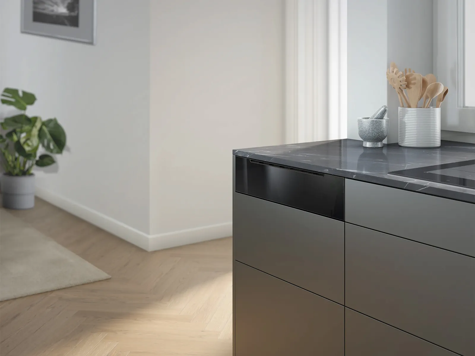 Cucina moderna con un piano di lavoro scuro, piano cottura a induzione e pavimento in legno chiaro.