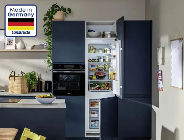 Constructa Einbau Kühl-Gefrier-Kombination mit geöffneter Tür in einer modernen, blauen Küche. Mit "Made in Germany" Logo.