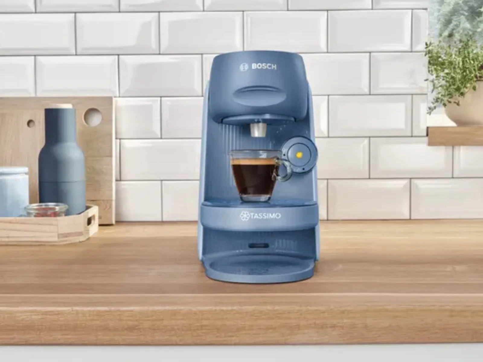 La cafetera TASSIMO FINESSE sobre la encimera de la cocina, acompañada de una taza de espresso llena.