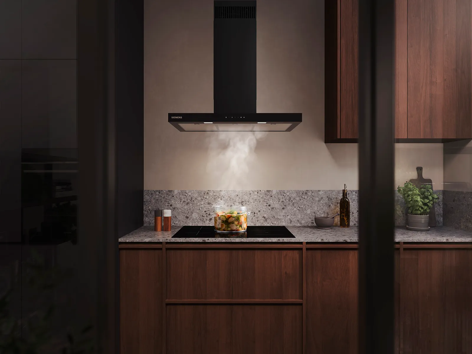 Modernt kök med en glasgryta med grönsaker som ångar på en induktionshäll under en fläktkåpa.