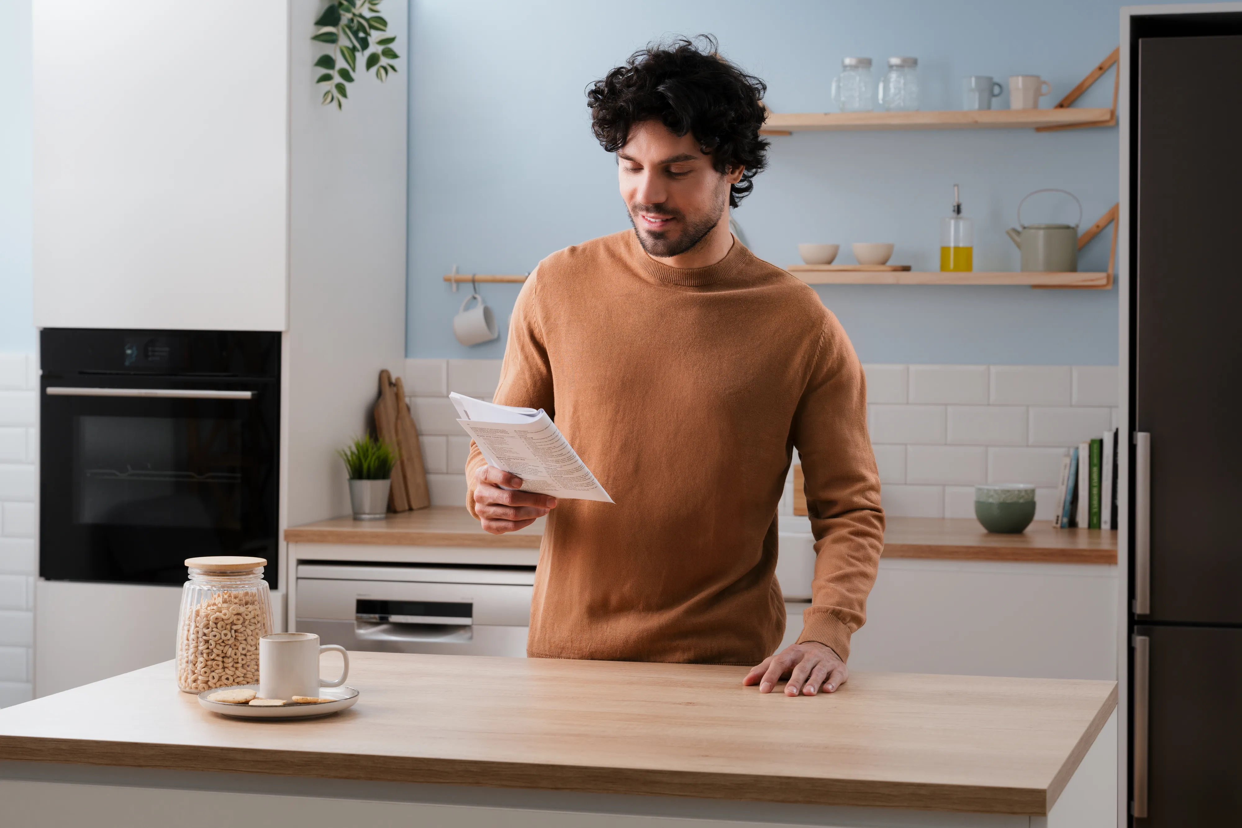 Mees loeb köögis kasutusjuhendit, taustal on näha sisseehitatud ahi.