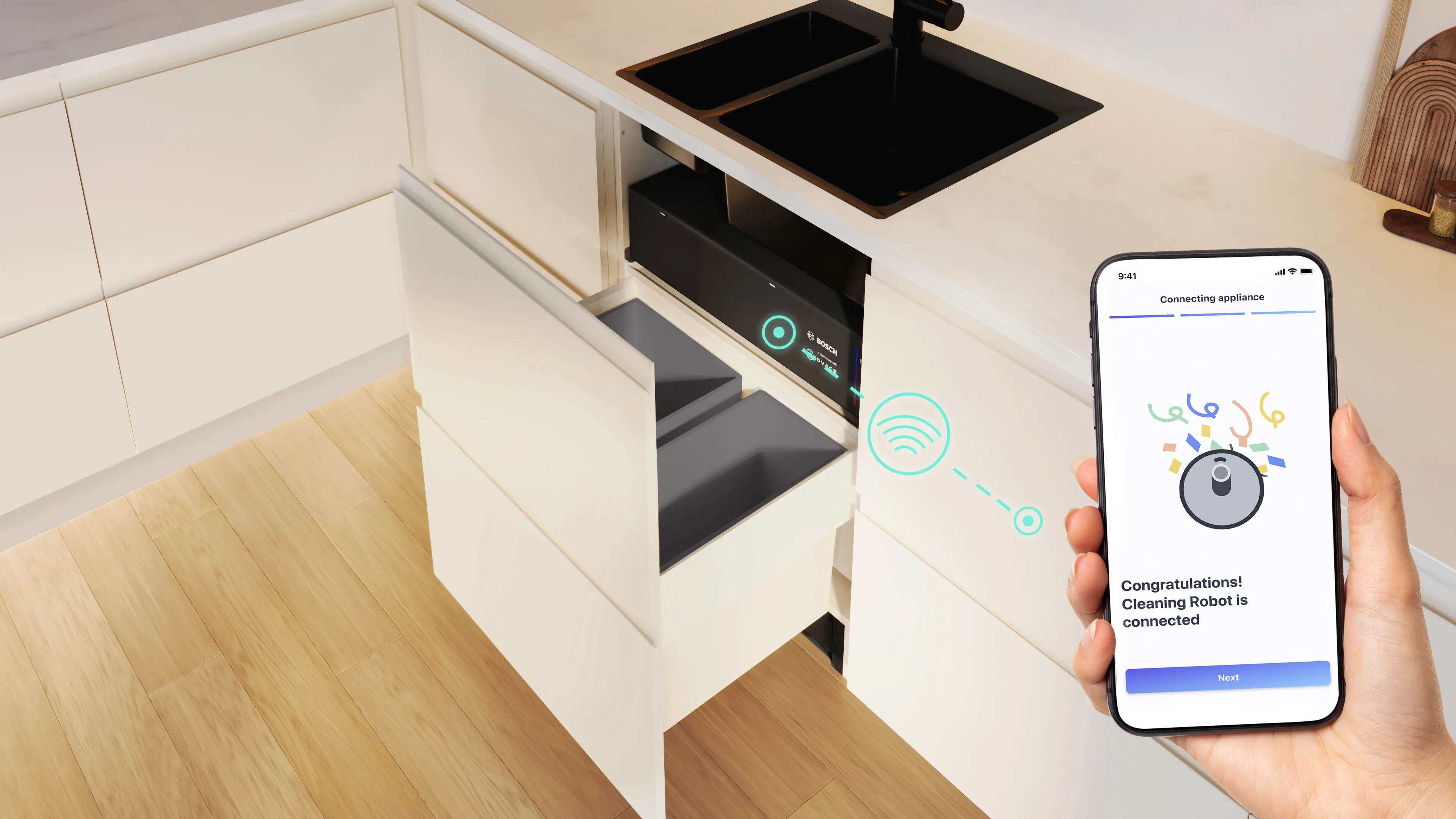 Una mano tiene in mano uno smartphone che mostra una notifica che un robot per la pulizia è collegato, in una cucina moderna con cassetti aperti e un lavandino. Simbolo Wi-Fi visibile.