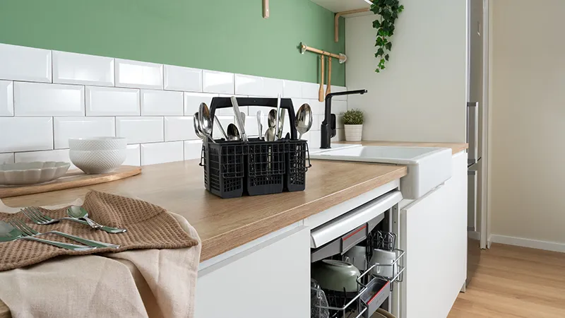 alt-Ett modernt kök med grön vägg, vit skåpinredning och en öppen diskmaskin.