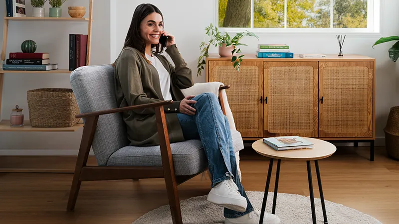 alt-En kvinna sitter i en fåtölj och pratar i telefon.