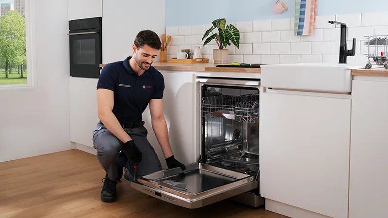alt-En servicetekniker från Bosch reparerar en diskmaskin.
