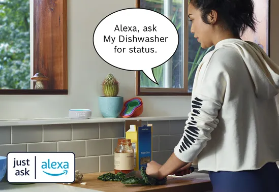 Woman interacting with Alexa device in kitchen, asking for dishwasher status.