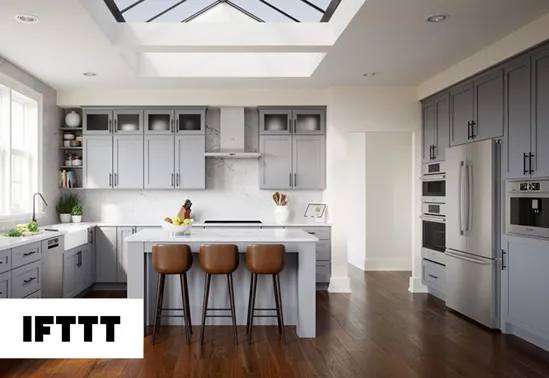 Modern kitchen with gray cabinets, island with brown stools, wooden floor, and skylight.