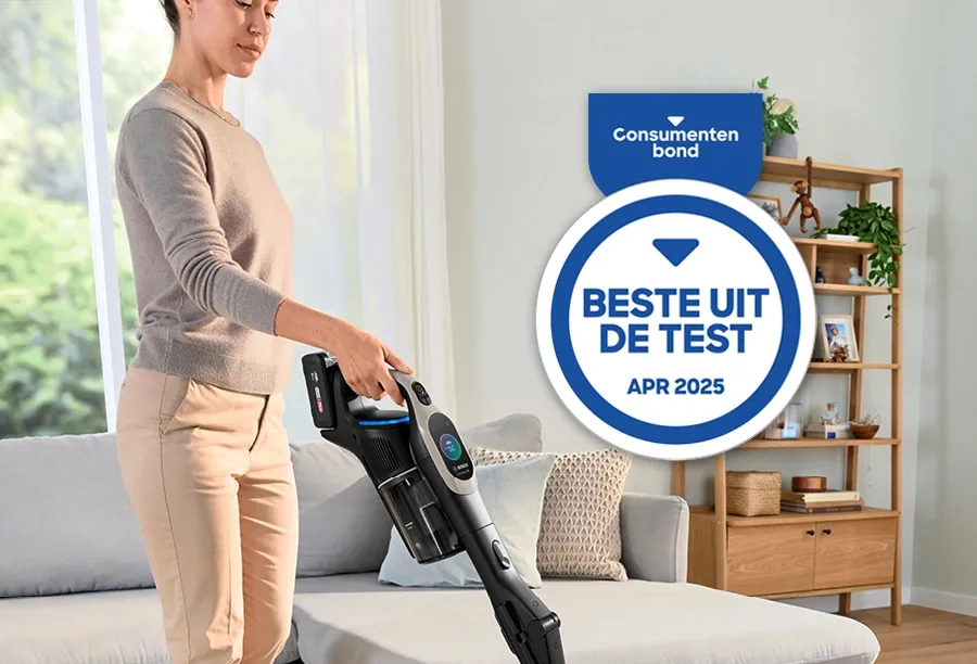 Een vrouw gebruikt een snoerloze stofzuiger op een tapijt terwijl een “Beste uit de test”-badge de kwaliteit benadrukt 