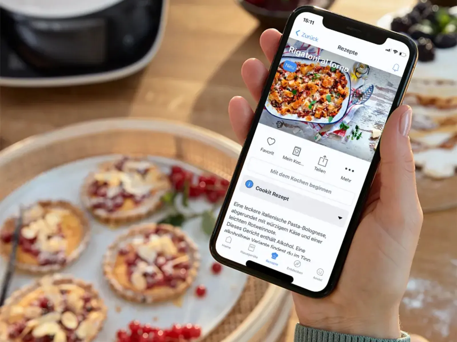 Persona che tiene in mano uno smartphone e visualizza un'app per la consegna di cibo, con fette di pizza fatta in casa su una tavola di legno sullo sfondo.