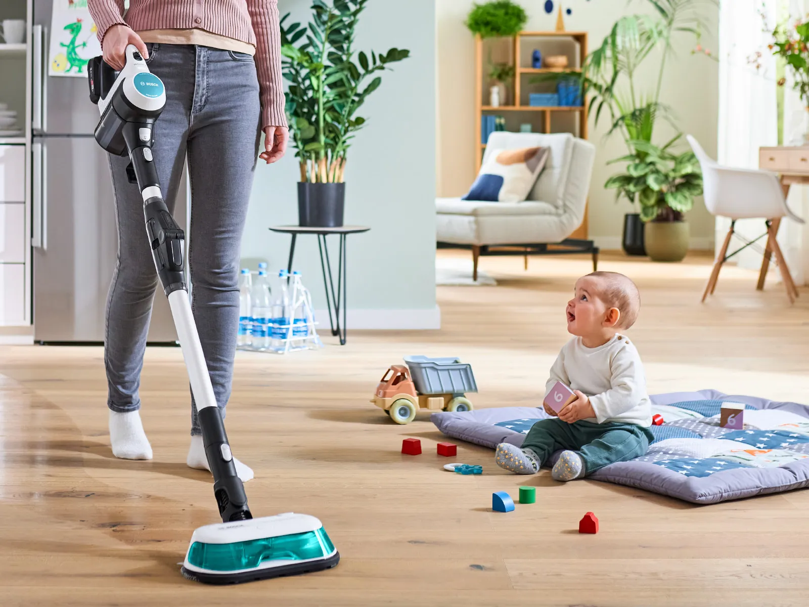 Mutter reinigt den Boden in der Nähe eines Babys.