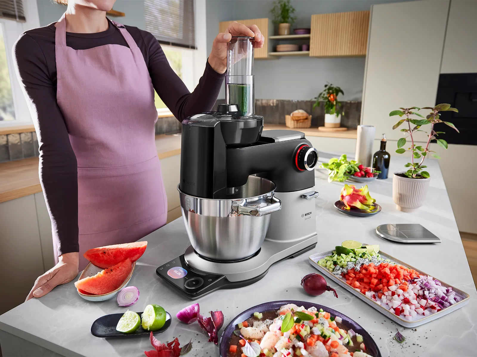 Le robot pâtissier Série 8 est posé sur un plan de travail de cuisine, entouré de divers fruits et légumes coupés, tandis qu'une personne utilise l'accessoire coupe-dés.